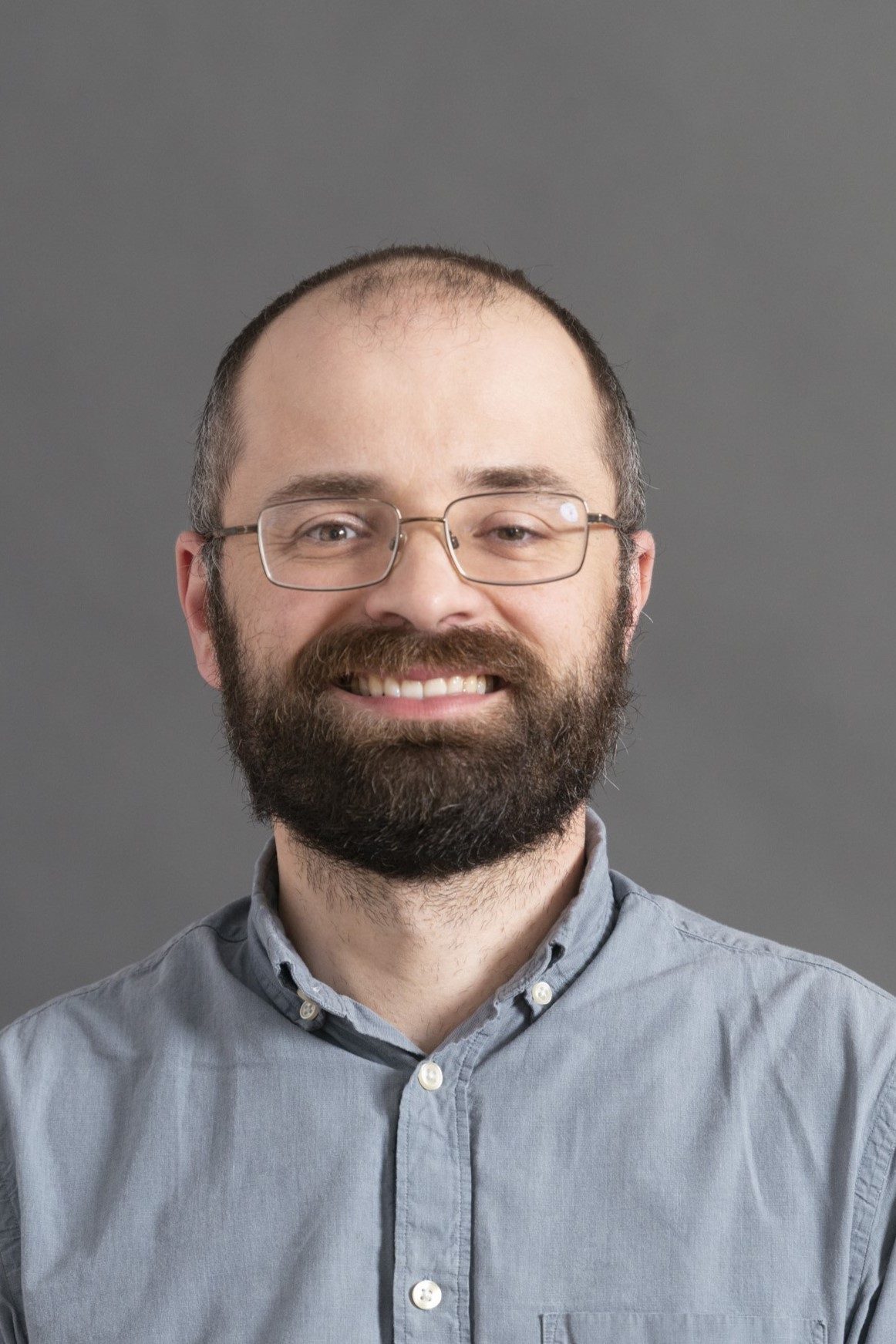 Man smiling with beard and glasses